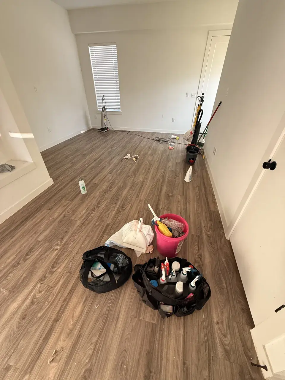 DURING: vinyl plank hallway with cleaning supplies mid-way through a move-out clean