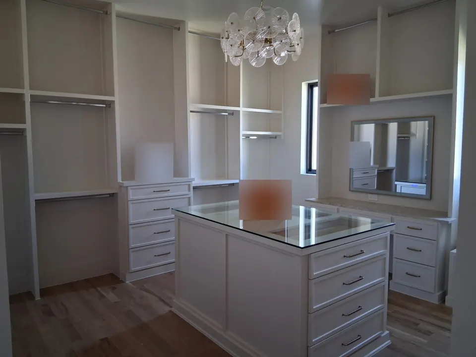 Clean walk-in closet with center island and glass top