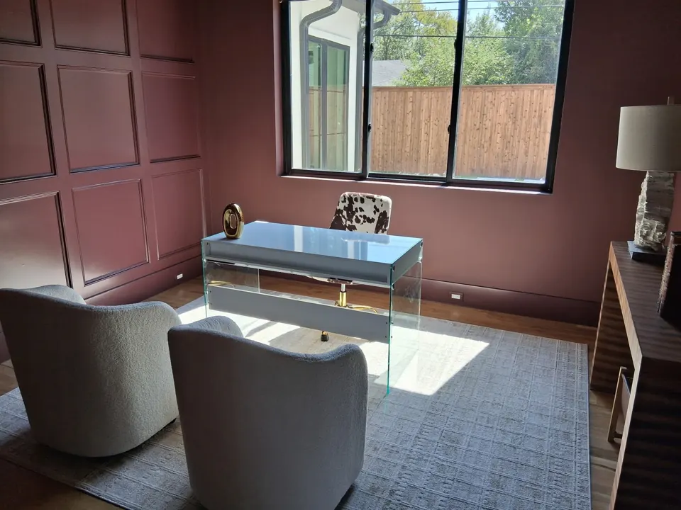 Clean, polished home office with mauve walls and glass desk