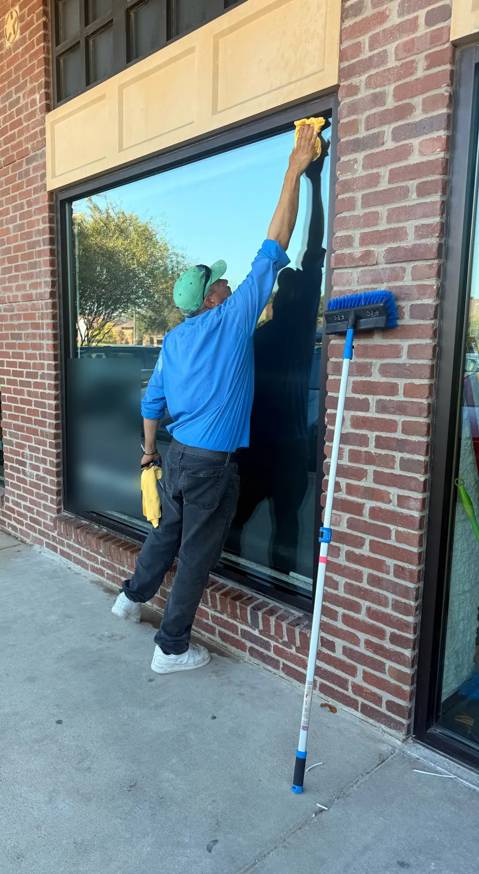 Famous Pink Cleaning team member cleaning a storefront window